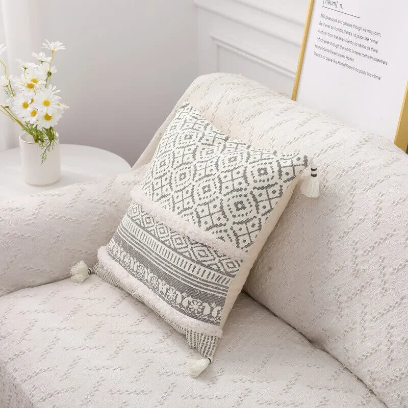 Funda de cojín boho étnico en blanco y gris claro con flecos.