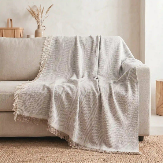 Colcha multiusos beige utilizada como cubre sofá protector en un salón. Caída natural del tejido de algodón que aporta calidez y protege la tapicería.