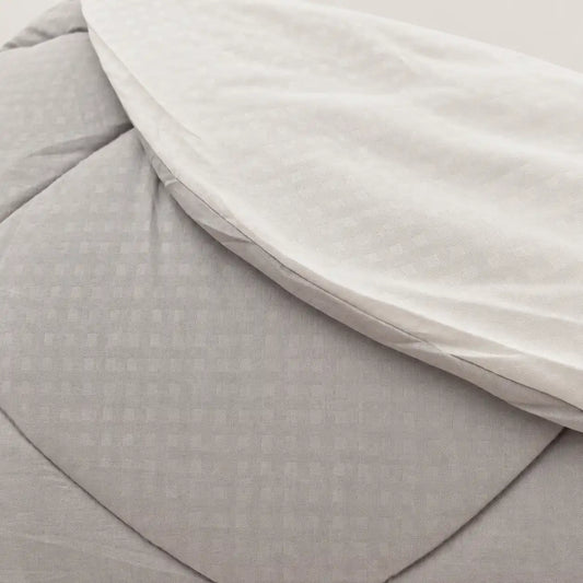 Primer plano del tejido extrasuave de microfibra en gris, destacando el práctico cosido a cuadros que mantiene la fibra térmica en su sitio.