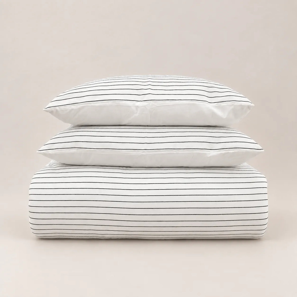 Edredón de invierno con diseño jacquard de rayas finas, doblado ordenadamente con sus dos fundas de almohada a juego en la parte superior.