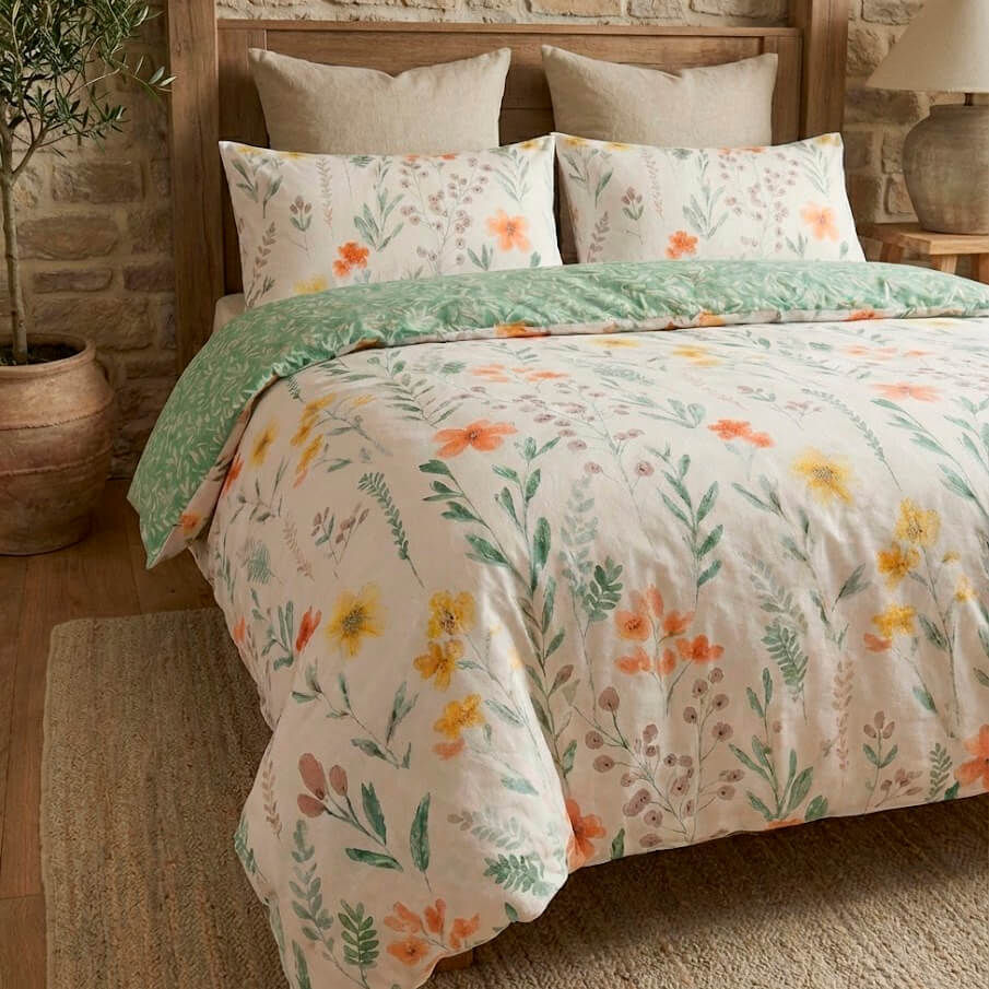 Funda nórdica con estampado de flores amarillas y naranjas en cama de matrimonio.