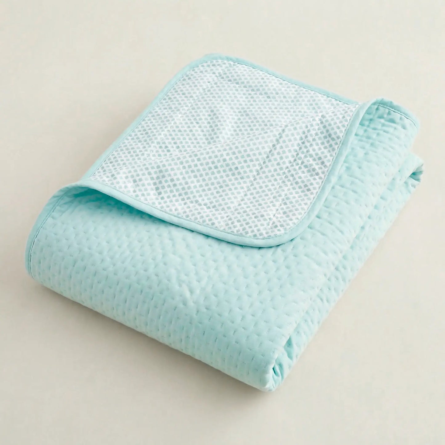 Primer plano de las costuras y el acolchado fino de la colcha verde menta clara