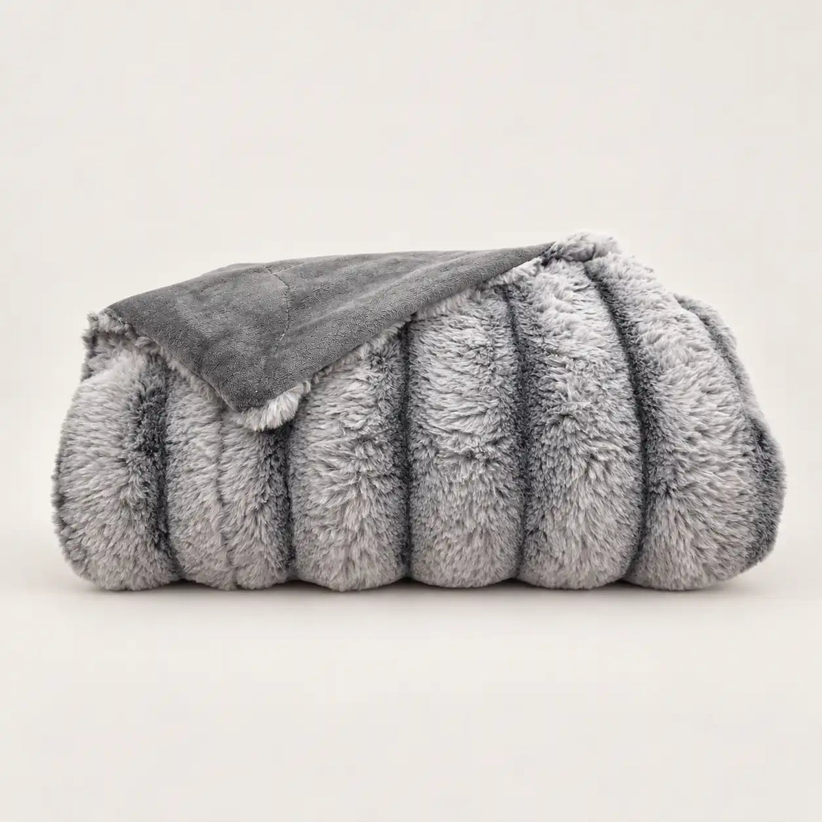 Manta gris reversible con la cara de pelo con relieve y el reverso polar visibles.