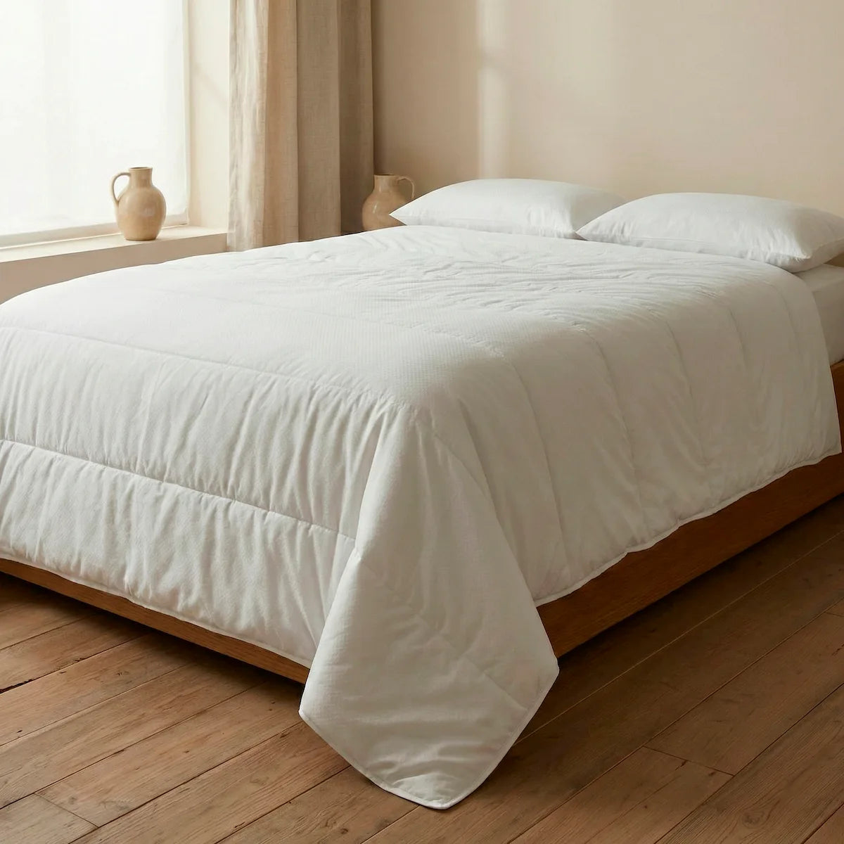 Cama de matrimonio vestida con el relleno nórdico ecológico de verano 100gr de Oma Home, mostrando su ligereza y caída natural en color blanco.